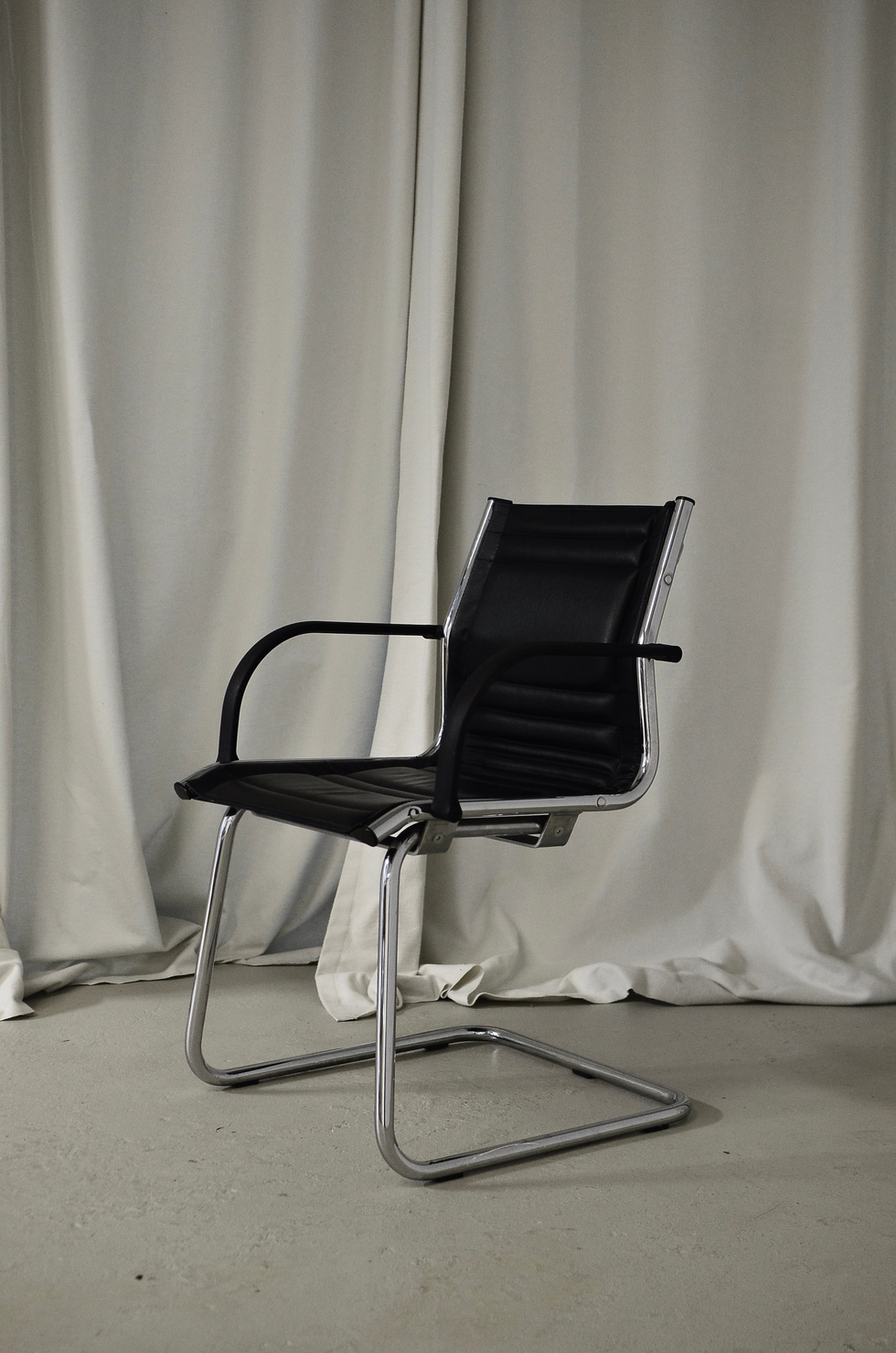 Black chair placed in room against curtain